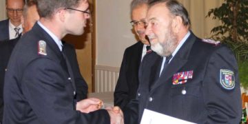 KFV-Vorsitzender Robert Buder steckt Peter Schützke das Ehrenkreuz des DFV in Gold an