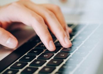 Hand auf der Tastatur eines Laptops