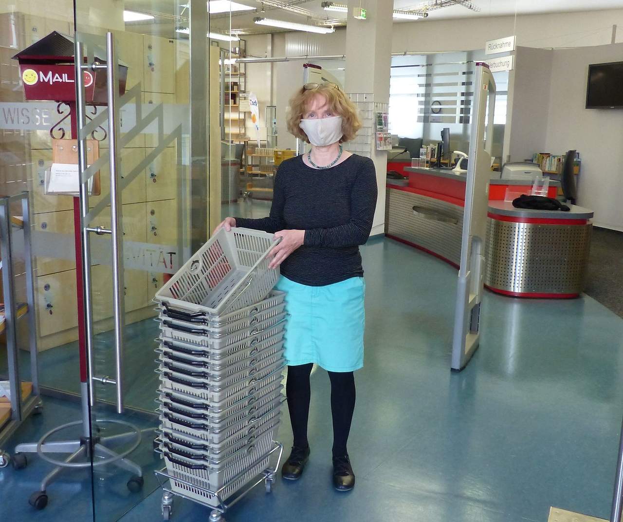 Mit Mundschutz ist ein zügiger Medientausch ab kommendem Freitag wieder möglich in der Stadt- und Regionalbibliothek Cottbus. Bibliotheksmitarbeiterin Kerstin Stöckel probt schon mal die Wiedereröffnung in besonderen Zeiten.; Foto: copy Jördis Klose