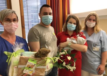 Hebamme Ines Linse und Pflegeschülerin Phoebe Richter überreichen den glücklichen Eltern ein Präsent des Carl-Thiem-Klinikums