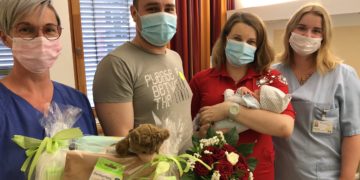Hebamme Ines Linse und Pflegeschülerin Phoebe Richter überreichen den glücklichen Eltern ein Präsent des Carl-Thiem-Klinikums
