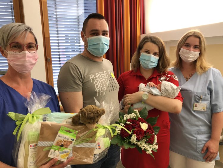 Hebamme Ines Linse und Pflegeschülerin Phoebe Richter überreichen den glücklichen Eltern ein Präsent des Carl-Thiem-Klinikums