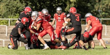 American-Football-Spieler der Cottbus Crayfish in Rot im Zweikampf mit einem Team in Schwarz