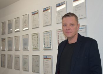 Geschäftsführer Holger Mylius vor der unternehmensinternen "Wall of Fame": Im Gang des Betriebsgebäudes werden die Abschlüsse, Qualifizierungen und Erfolge der Mitarbeitenden für alle sichtbar präsentiert. Ein Ansporn für alle, die auf dieser Wand noch nicht vertreten sind, HWK Cottbus/Veronika Martin