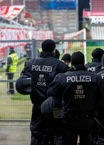 Polizeikräfte gehen im Stadion der Freundschaft in Cottbus an einem Fanblock entlang