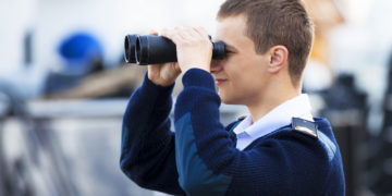 Ein junger Mann in Uniform schaut durch ein Fernglas.