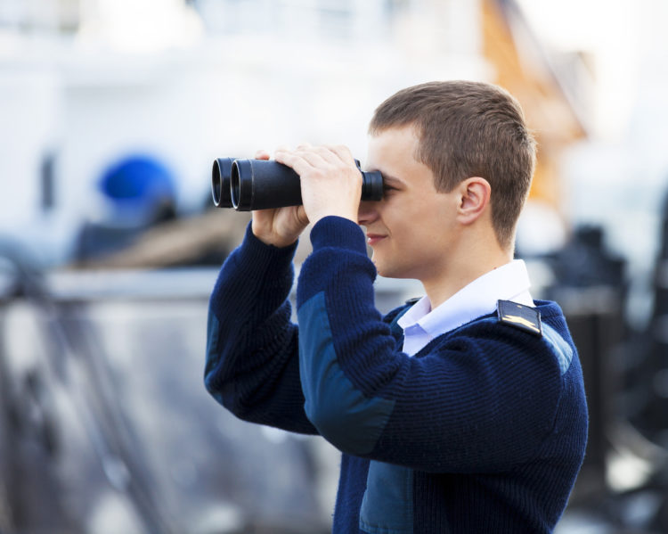 Ein junger Mann in Uniform schaut durch ein Fernglas.