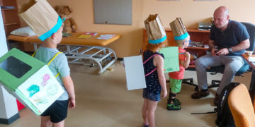 Die drei- bis sechsjährigen Patienten kreierten während der Petö-Therapie Salatboxen
und lieferten sie im Haus aus. Hier führen sie ihre gebastelten Produkte dem Chefarzt des
Sozialpädiatrischen Zentrums Cottbus, Dr. Georg Schwabe, vor. (Bild: Irina Kabelitz)