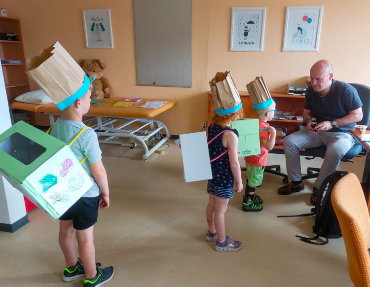Die drei- bis sechsjährigen Patienten kreierten während der Petö-Therapie Salatboxen
und lieferten sie im Haus aus. Hier führen sie ihre gebastelten Produkte dem Chefarzt des
Sozialpädiatrischen Zentrums Cottbus, Dr. Georg Schwabe, vor. (Bild: Irina Kabelitz)