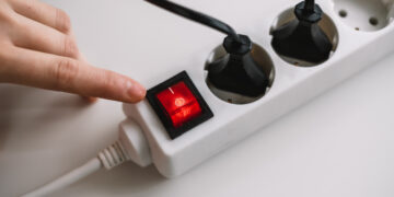 Hand turns on an electric surge protector. Protection of household appliances from electrical interference. Home safety