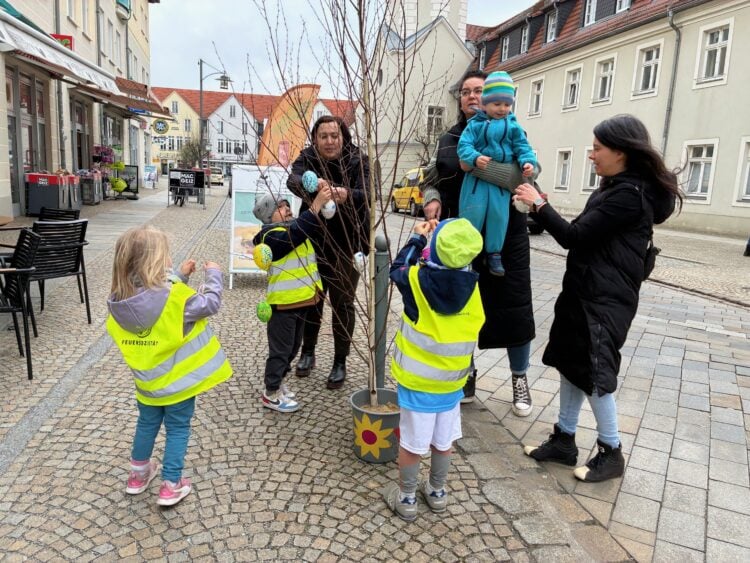 Kita-Kinder haben in der Innenstadt von Spremberg bunte Eier aus Kunststoff an kleinen Birken aufgehängt. Mit großer Begeisterung halfen unter anderem die Mädchen und Jungen aus der Kita Graustein dabei, das Stadtzentrum zu schmücken. (Bild: ASG Spremberg GmbH/Tobias Roitsch)