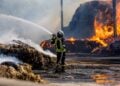 Feuerwehrmann bekämpft die Flammen am brennenden Strohlager in Großkmehlen