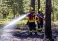 Feuerwehrmann löscht den Waldbodenbrand bei Alt-Schadow
