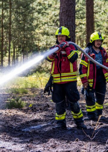 Feuerwehrmann löscht den Waldbodenbrand bei Alt-Schadow