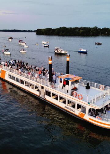 Ausflugsschiff und geschmückte Boote beim Bootskorso auf dem Schwielochsee