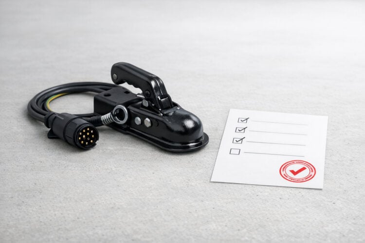 Anhängerkupplung mit 13-poligem Stecker neben abgehakter Prüf-Checkliste