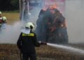 Feuerwehrmann löscht brennende Strohballen in Spree-Neiße