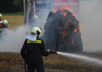 Feuerwehrmann löscht brennende Strohballen in Spree-Neiße
