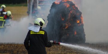 Feuerwehrmann löscht brennende Strohballen in Spree-Neiße