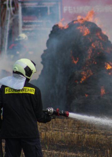 Feuerwehrmann löscht brennende Strohballen in Spree-Neiße