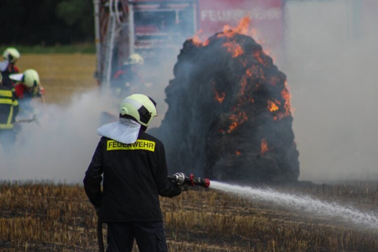 Feuerwehrmann löscht brennende Strohballen in Spree-Neiße