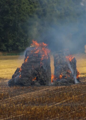 Einsatzkräfte an den brennenden Strohballen