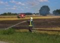 Feuerwehrmann mit Strahlrohr am Feldrand