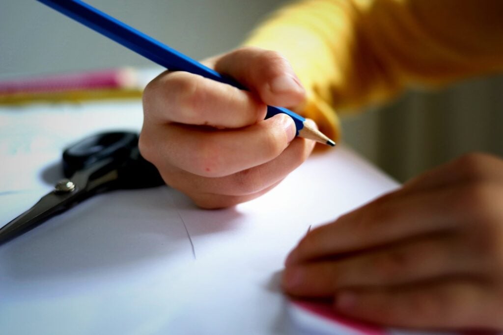 Kinderhände mit Stift an einem Schreibtisch