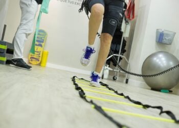 Patient mit Knieorthese trainiert in einer Physiotherapiepraxis an einer Koordinationsleiter