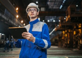 Techniker mit Schutzhelm und Tablet in einer Industrieanlage