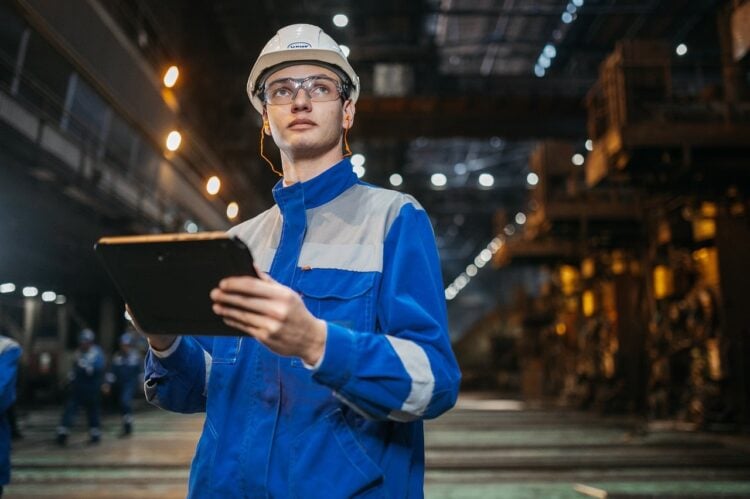 Techniker mit Schutzhelm und Tablet in einer Industrieanlage