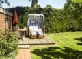 Ein Strandkorb steht windgeschützt in einem gepflegten Garten