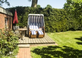 Ein Strandkorb steht windgeschützt in einem gepflegten Garten