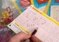 Hand kreuzt Zahlen auf einem LOTTO-Spielschein 6 aus 49 an