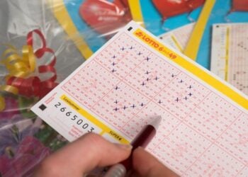 Hand kreuzt Zahlen auf einem LOTTO-Spielschein 6 aus 49 an