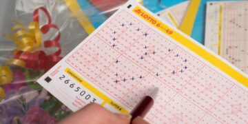 Hand kreuzt Zahlen auf einem LOTTO-Spielschein 6 aus 49 an