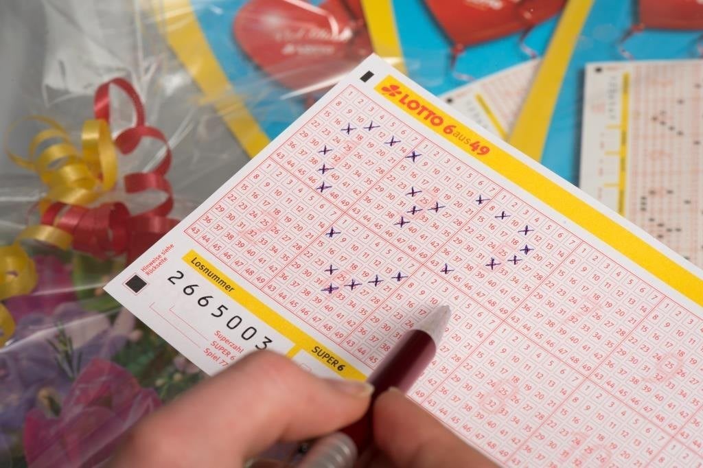 Hand kreuzt Zahlen auf einem LOTTO-Spielschein 6 aus 49 an