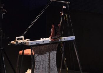 Eine umgebaute Strickmaschine erzeugt eine lange, beschriftete Textilbahn