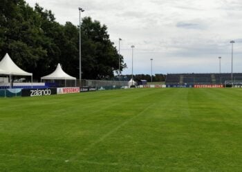 Fußballplatz mit temporären Tribünen, Pagodenzelten und Bandenwerbung
