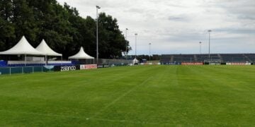 Fußballplatz mit temporären Tribünen, Pagodenzelten und Bandenwerbung