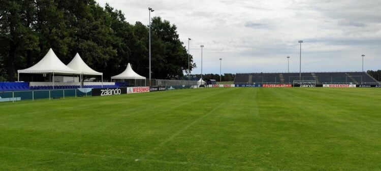 Fußballplatz mit temporären Tribünen, Pagodenzelten und Bandenwerbung