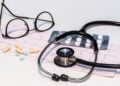 Ein EKG-Ausdruck mit Stethoskop, Brille und Tabletten auf einem Tisch
