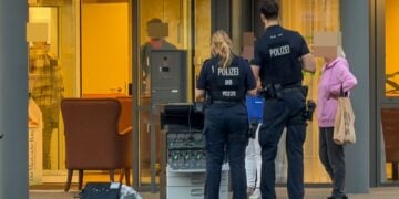 Polizisten vor dem Eingang eines Pflegeheims, davor ein Gerät mit Brandspuren