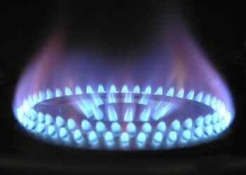Blaue Gasflamme eines Gasherdbrenners vor dunklem Hintergrund