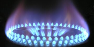 Blaue Gasflamme eines Gasherdbrenners vor dunklem Hintergrund