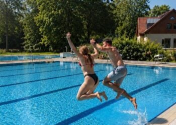 Zwei Badegaeste springen ins Schwimmerbecken des Freibads Ortrand