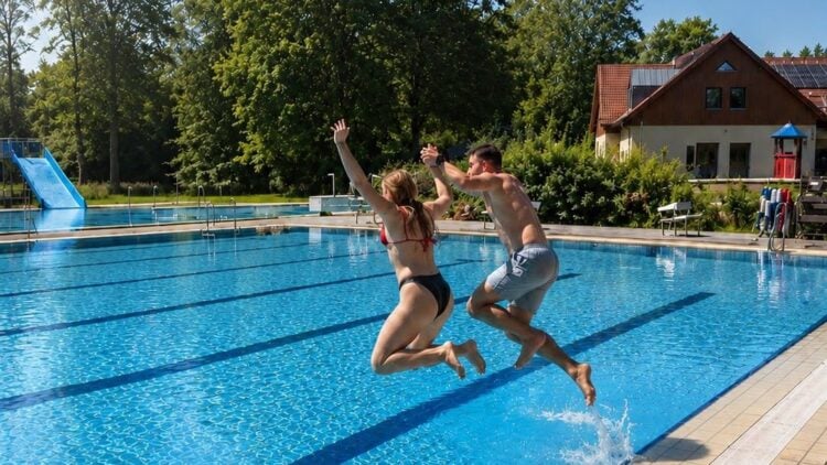 Zwei Badegaeste springen ins Schwimmerbecken des Freibads Ortrand