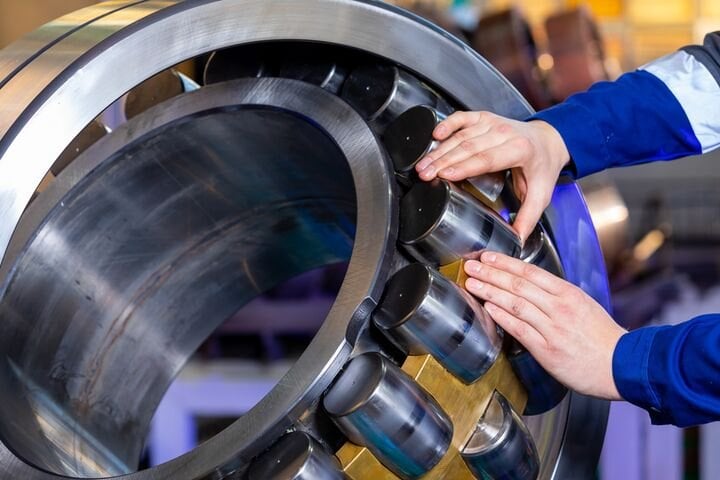 Hände arbeiten an einem großen Wälzlager eines Schienenfahrzeugs
