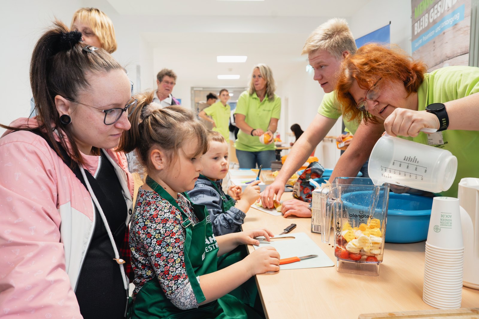 Kinder und Erwachsene bereiten an einem Stand gemeinsam Obst zu