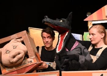 Zwei Spieler fuehren eine Wolfspuppe und eine Schweinepuppe zwischen Pappkartons